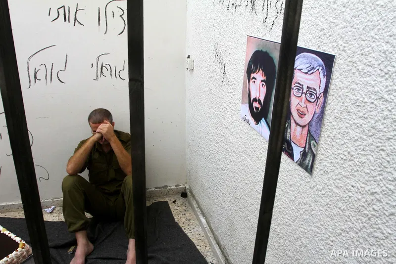 A Palestinian playing the role of Israeli soldier Gilad Shalit stands in a cage to mark the fifth anniversary of his capture by Palestinian militants, in Jabalya in the northern Gaza Strip June 25, 2011. The Hebrew writi...
