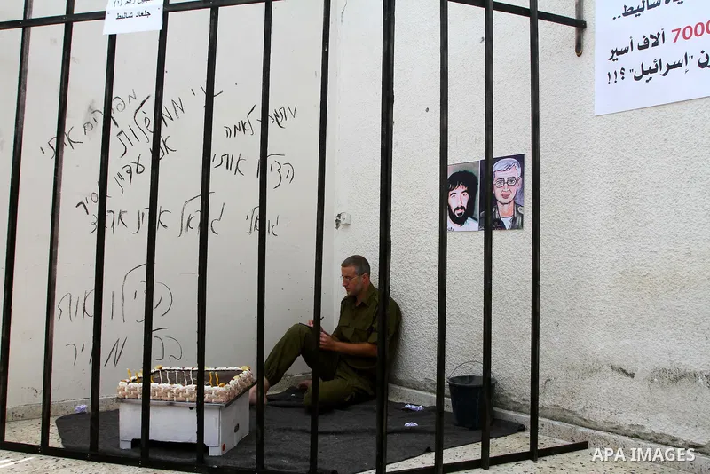 A Palestinian playing the role of Israeli soldier Gilad Shalit stands in a cage to mark the fifth anniversary of his capture by Palestinian militants, in Jabalya in the northern Gaza Strip June 25, 2011. The Hebrew writi...