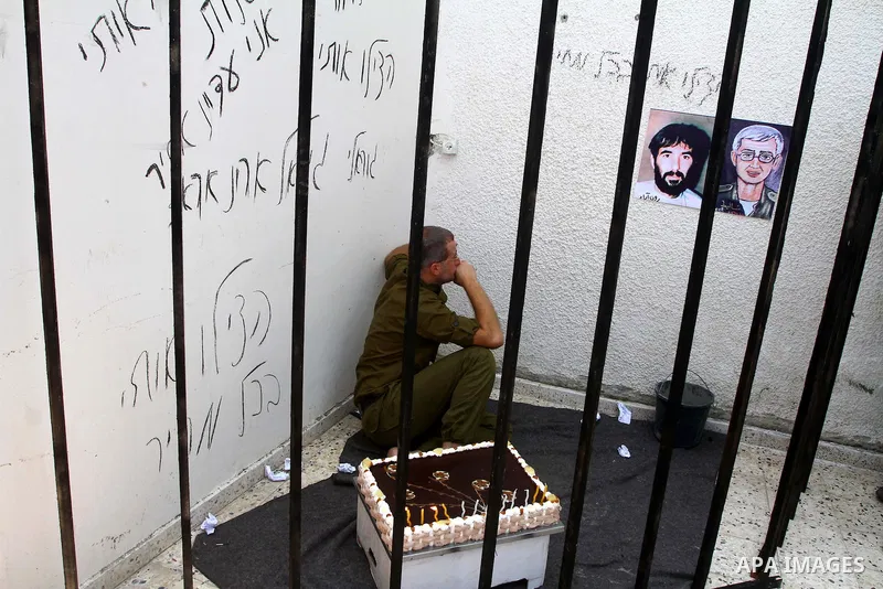 A Palestinian playing the role of Israeli soldier Gilad Shalit stands in a cage to mark the fifth anniversary of his capture by Palestinian militants, in Jabalya in the northern Gaza Strip June 25, 2011. The Hebrew writi...