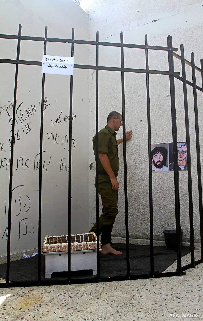 A Palestinian playing the role of Israeli soldier Gilad Shalit stands in a cage to mark the fifth anniversary of his capture by Palestinian militants, in Jabalya in the northern Gaza Strip June 25, 2011. The Hebrew writi...