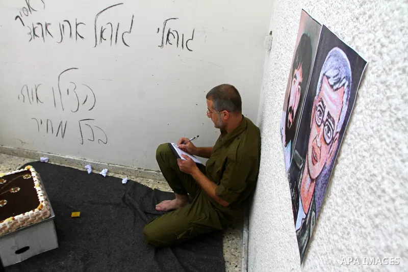 A Palestinian playing the role of Israeli soldier Gilad Shalit stands in a cage to mark the fifth anniversary of his capture by Palestinian militants, in Jabalya in the northern Gaza Strip June 25, 2011. The Hebrew writi...