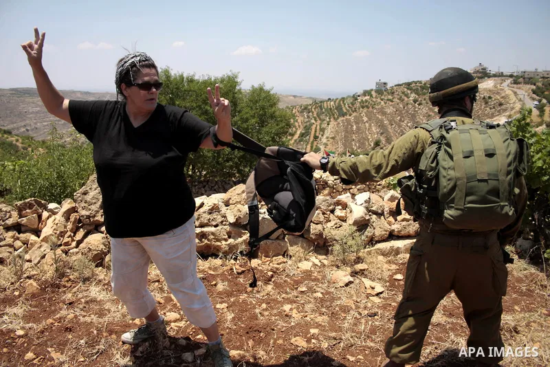 An Israeli soldier scuffles with a foreign activist during a demonstration against the demolishing of farm land to be used in the construction of Jewish settlements near the existing Israeli settlement of Karmi Tsor near...