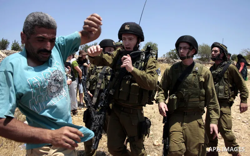 Israeli soldiers scuffles with a Palestinian protester during a demonstration against the demolishing of farm land to be used in the construction of Jewish settlements near the existing Israeli settlement of Karmi Tsor n...