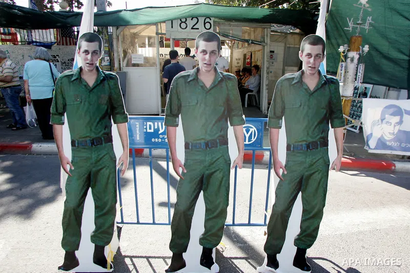 Israelis walk near a cardboard cutout of abducted Israeli soldier Gilad Shalit near Prime Minister Benjamin Netanyahu's residence in Jerusalem on June 25, 2011 as Israelis mark the 1,826th day (5th year) of his captivity...
