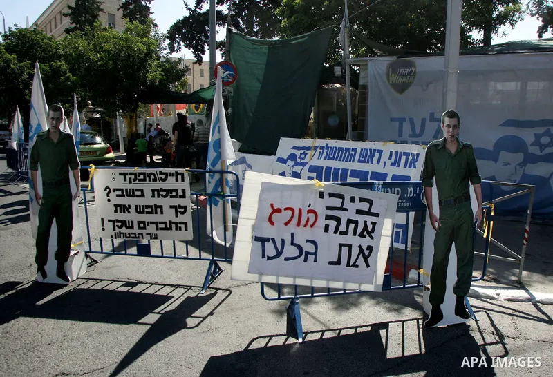 Israelis walk near the family's protest tent of abducted Israeli soldier Gilad Shalit near Prime Minister Benjamin Netanyahu's residence in Jerusalem on June 25, 2011 as Israelis mark the 1,826th day (5th year) of his ca...