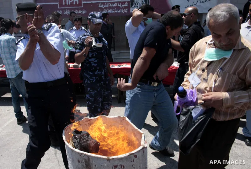 Palestinian police officers burn the confiscated drugs which include heroin, opium and marijuana during a campaign against illegal drugs in the West Bank city of Hebron, 26 June 2011. Photo by Najeh Hashlamoun ..