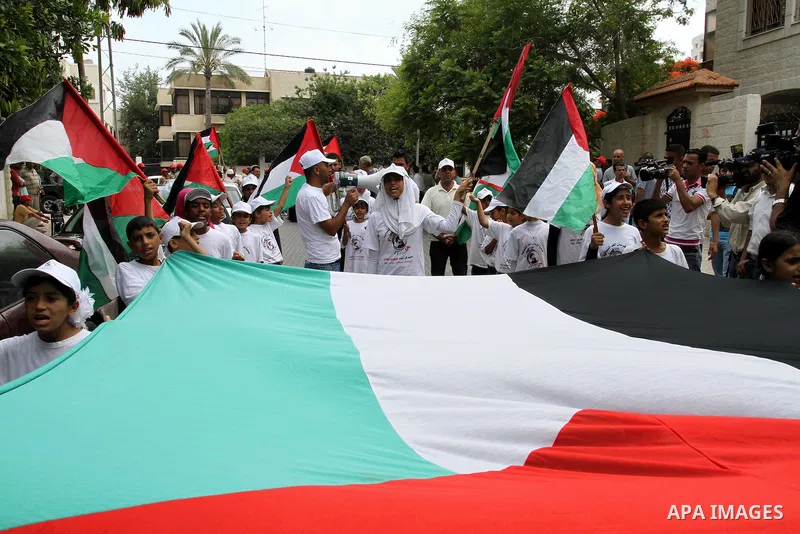 Palestinians from NGOs hold national flags during a protest in solidarity with freedom flotilla "2" and to break the seige in front of the UNRWA headquarters in Gaza city on June 27, 2011. Photo by Mohammed Asad