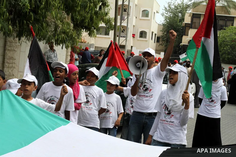Palestinians from NGOs hold national flags during a protest in solidarity with freedom flotilla (2) and to break the seige in front of the UNRWA in Gaza city on June 27, 2011. Photo by Mohammed Asad