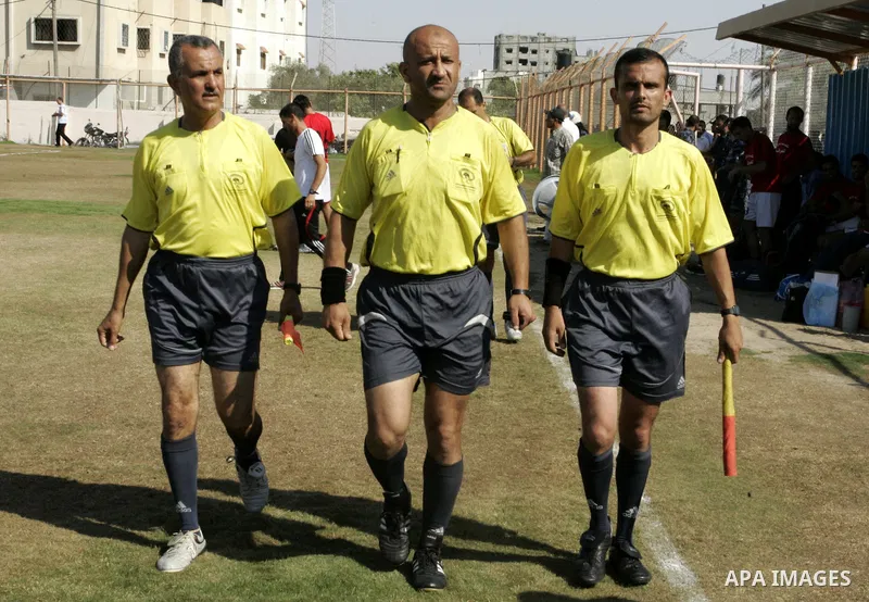 Palestinian football referees walk during a football match between Khan Yunis Youth club (red shirt) and Rafah Collective club (white shirt) on Jun 27, 2011 in the southern Gaza Strip town of Rafah. Photo by Abed Rahim K...