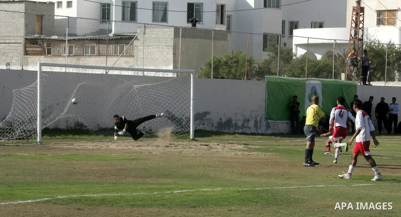 Palestinian football players challenge for the ball during a football match between Khan Yunis Youth club (red shirt) and Rafah Collective club (white shirt) on Jun 27, 2011 in the southern Gaza Strip town of Rafah. Phot...