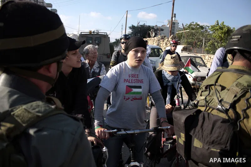 Palestinian and foreign bikers wait behind a cordon of Israeli security forces to ride their bicycles under the slogan of "biking without borders" across a Palestinian road closed off by Israeli troops to be used by Jewi...