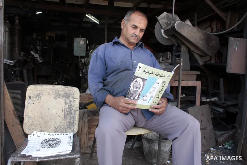 A Palestinian elderly man Elias Abdel-Hay reads a book at his shop as he prepares to study in the high school "Twajihi" after he left studing for 47 years old in the West Bank city of Hebron on June 29, 2011. Where he co...