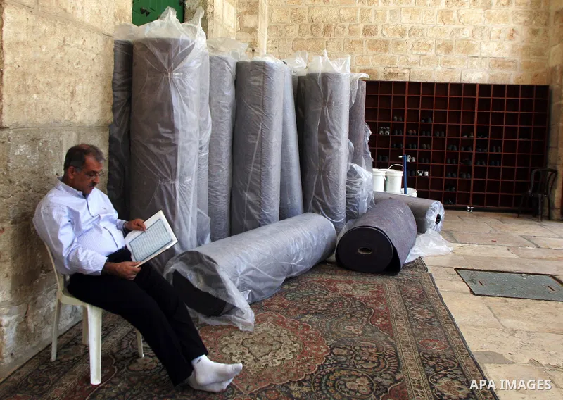 A Palestinian man sits inside the Al-Aqsa Mosque in Jerrusalem's old city on June 29, 2011 near rolls of new carpet that will be fitted inside the mosque. According to Sheikh Azzam Khatib, the head of the Islamic Waqf in...