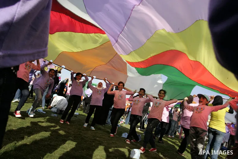 Palestinian children perform with coloured parachutes during summer camp activities supervised by the UN Relief and Works Agency (UNRWA) in Khan Yunis in the southern Gaza Strip on June 30, 2011. Photo by Abed Rahim Khat...