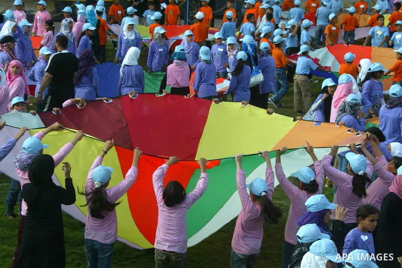 Palestinian children perform with coloured parachutes during summer camp activities supervised by the UN Relief and Works Agency (UNRWA) in Khan Yunis in the southern Gaza Strip on June 30, 2011. Photo by Abed Rahim Khat...