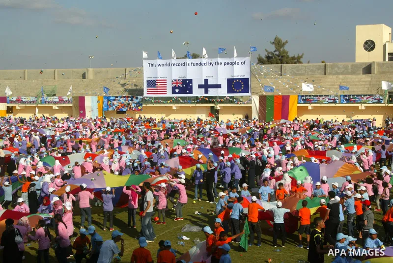 Palestinian children perform with coloured parachutes during summer camp activities supervised by the UN Relief and Works Agency (UNRWA) in Khan Yunis in the southern Gaza Strip on June 30, 2011. Photo by Abed Rahim Khat...