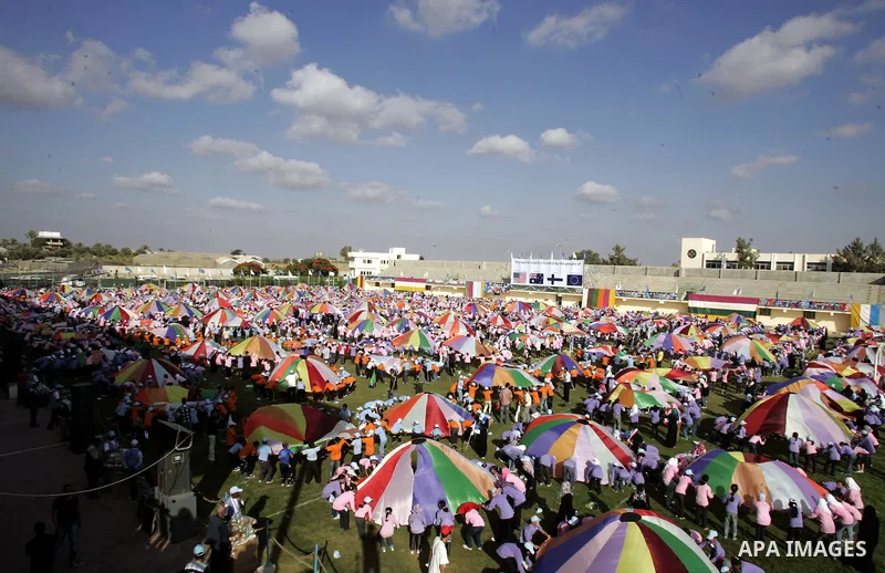 Palestinian children perform with coloured parachutes during summer camp activities supervised by the UN Relief and Works Agency (UNRWA) in Khan Yunis in the southern Gaza Strip on June 30, 2011. Photo by Ali Jadallah