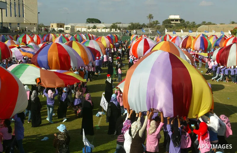 Palestinian children perform with coloured parachutes during summer camp activities supervised by the UN Relief and Works Agency (UNRWA) in Khan Yunis in the southern Gaza Strip on June 30, 2011. Photo by Abed Rahim Khat...