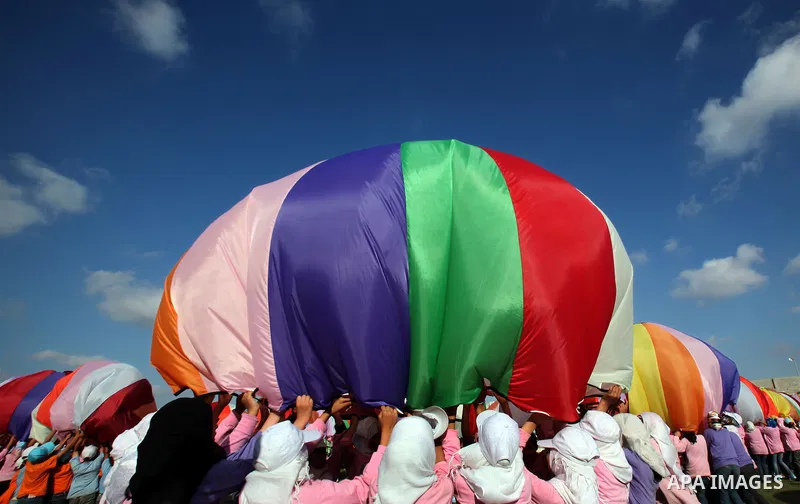 Palestinian children perform with coloured parachutes during summer camp activities supervised by the UN Relief and Works Agency (UNRWA) in Khan Yunis in the southern Gaza Strip on June 30, 2011. Photo by Ali Jadallah
