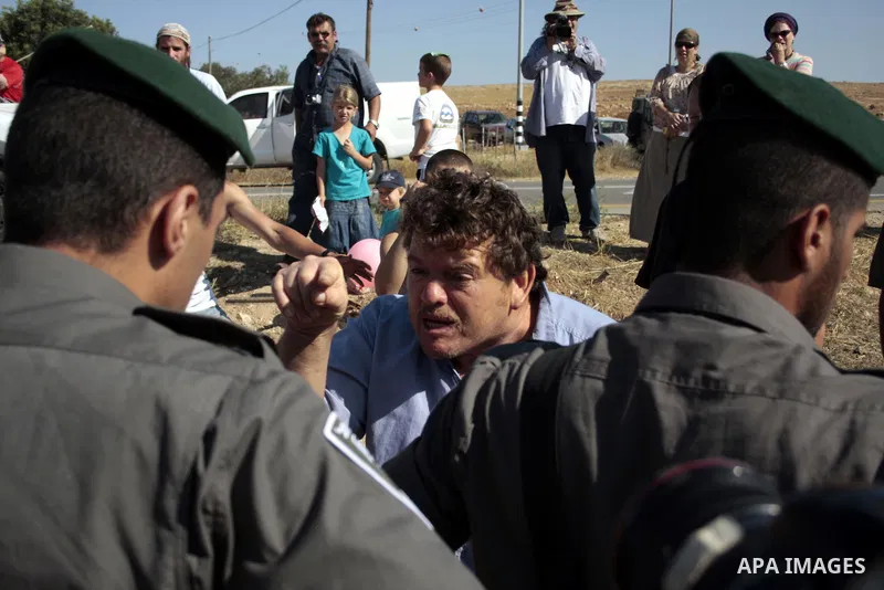 Israeli soldiers and an Israeli settler argue as security forces evacuate a group of Jewish settlers who tried to make a sit-in on a Palestinian land that was being cultivated by Palestinian farmers, on July 1, 2011 in t...