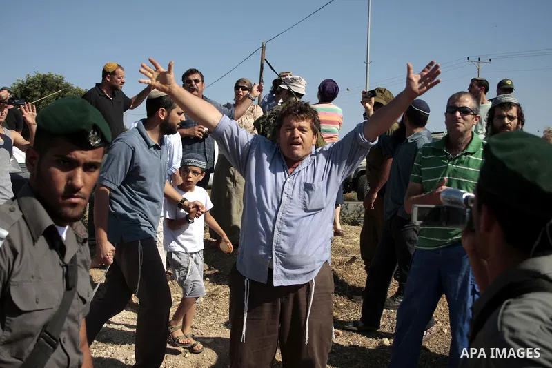 Israeli soldiers and an Israeli settler argue as security forces evacuate a group of Jewish settlers who tried to make a sit-in on a Palestinian land that was being cultivated by Palestinian farmers, on July 1, 2011 in t...