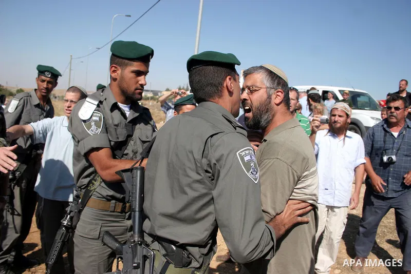 Israeli soldiers and an Israeli settler argue as security forces evacuate a group of Jewish settlers who tried to make a sit-in on a Palestinian land that was being cultivated by Palestinian farmers, on July 1, 2011 in t...