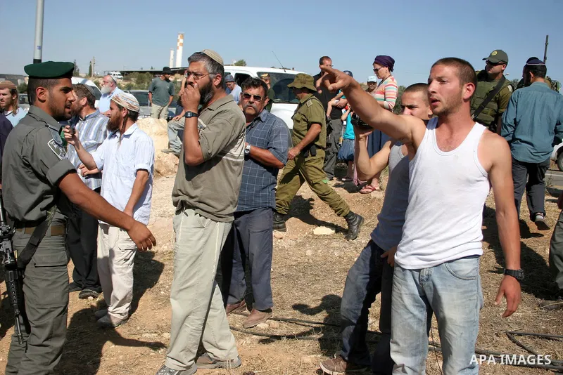 Israeli soldiers and an Israeli settler argue as security forces evacuate a group of Jewish settlers who tried to make a sit-in on a Palestinian land that was being cultivated by Palestinian farmers, on July 1, 2011 in t...