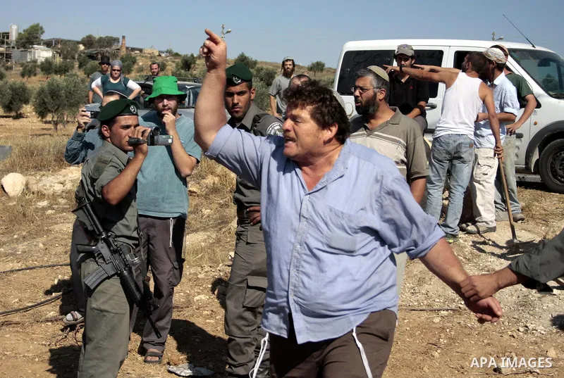 Israeli soldiers and an Israeli settler argue as security forces evacuate a group of Jewish settlers who tried to make a sit-in on a Palestinian land that was being cultivated by Palestinian farmers, on July 1, 2011 in t...