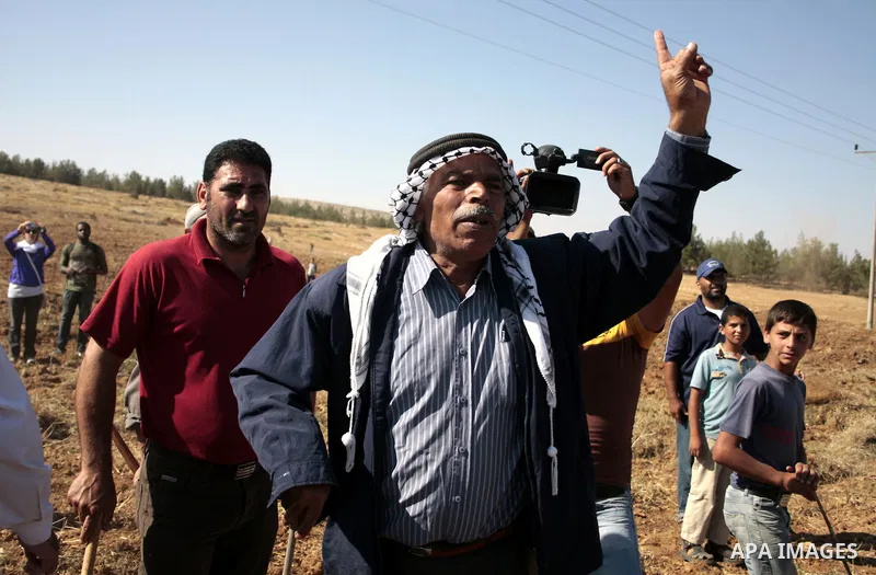 Palestinian farmers work at their land as Israeli border guards prepare to evacuate Jewish settlers who tried to make a sit-in on a Palestinian land that was being cultivated by farmers, on July 1, 2011, in the West Bank...