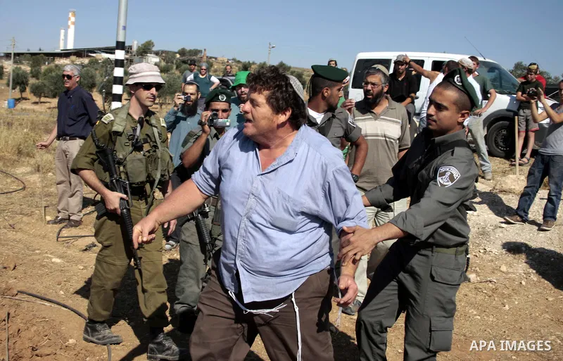 Israeli soldiers and an Israeli settler argue as security forces evacuate a group of Jewish settlers who tried to make a sit-in on a Palestinian land that was being cultivated by Palestinian farmers, on July 1, 2011 in t...