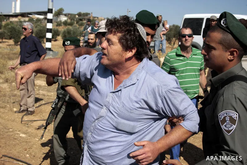 Israeli soldiers and an Israeli settler argue as security forces evacuate a group of Jewish settlers who tried to make a sit-in on a Palestinian land that was being cultivated by Palestinian farmers, on July 1, 2011 in t...