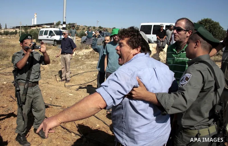 Israeli soldiers and an Israeli settler argue as security forces evacuate a group of Jewish settlers who tried to make a sit-in on a Palestinian land that was being cultivated by Palestinian farmers, on July 1, 2011 in t...