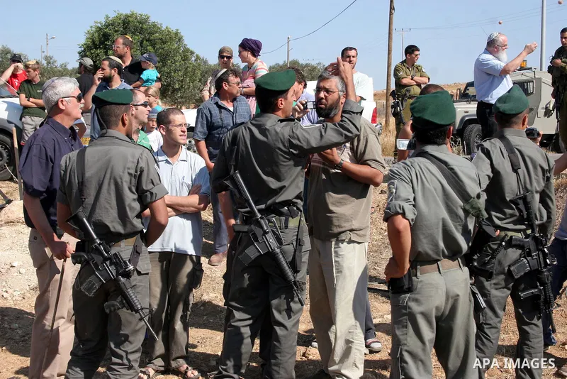 Israeli soldiers and an Israeli settler argue as security forces evacuate a group of Jewish settlers who tried to make a sit-in on a Palestinian land that was being cultivated by Palestinian farmers, on July 1, 2011 in t...