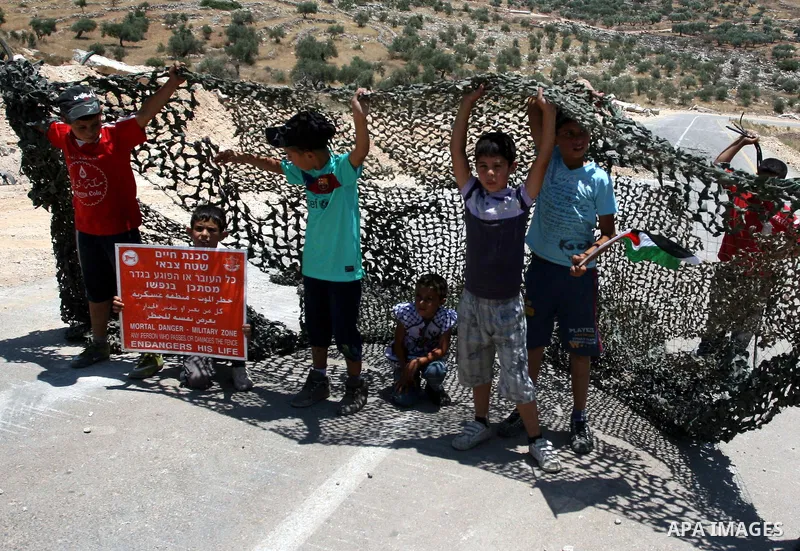 Palestinian demonstrators celebrate at the site where Israeli forces ripped down part of its controversial separation barrier outside the West Bank village of Bilin, the focus of anti-barrier protests, on July 1, 2011. I...