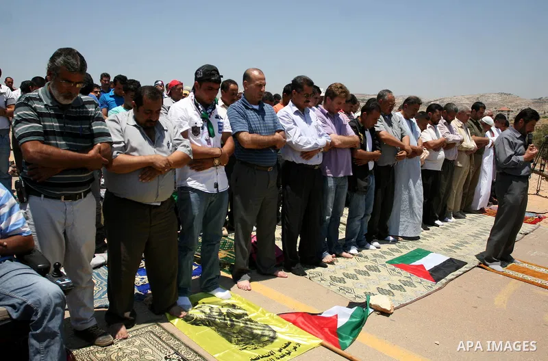 Palestinian demonstrators attend Friday prayers as they gather at the site where Israeli forces ripped down part of its controversial separation barrier outside the West Bank village of Bilin, the focus of anti-barrier p...