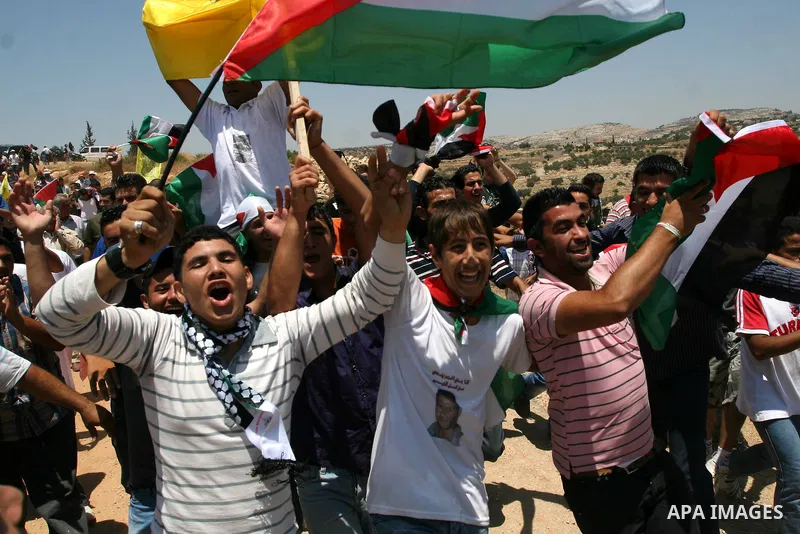 Palestinian demonstrators celebrate at the site where Israeli forces ripped down part of its controversial separation barrier outside the West Bank village of Bilin, the focus of anti-barrier protests, on July 1, 2011. I...