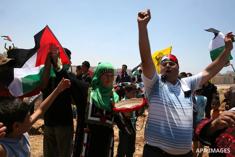 Palestinian demonstrators celebrate at the site where Israeli forces ripped down part of its controversial separation barrier outside the West Bank village of Bilin, the focus of anti-barrier protests, on July 1, 2011. I...