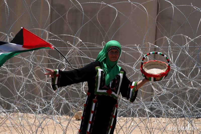 A Palestinian woman celebrates at the site where Israeli forces ripped down part of its controversial separation barrier outside the West Bank village of Bilin, the focus of anti-barrier protests, on July 1, 2011. Israel...