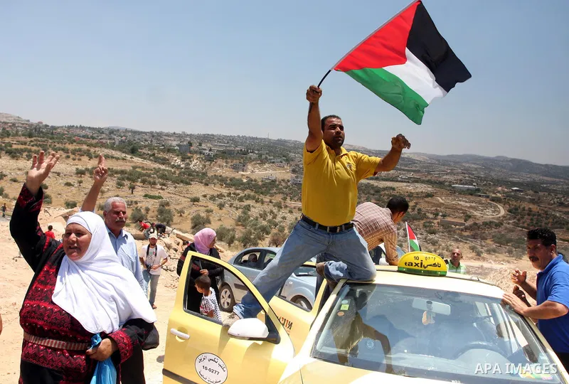 Palestinian demonstrators celebrate at the site where Israeli forces ripped down part of its controversial separation barrier outside the West Bank village of Bilin, the focus of anti-barrier protests, on July 1, 2011. I...