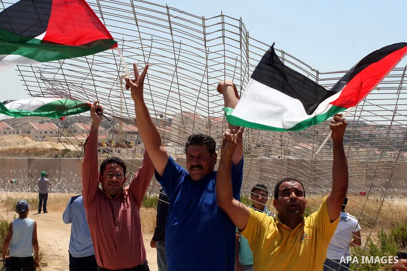 Palestinian demonstrators celebrate at the site where Israeli forces ripped down part of its controversial separation barrier outside the West Bank village of Bilin, the focus of anti-barrier protests, on July 1, 2011. I...
