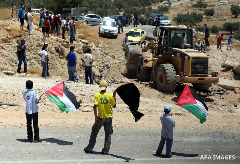 Palestinian demonstrators celebrate at the site where Israeli forces ripped down part of its controversial separation barrier outside the West Bank village of Bilin, the focus of anti-barrier protests, on July 1, 2011. I...