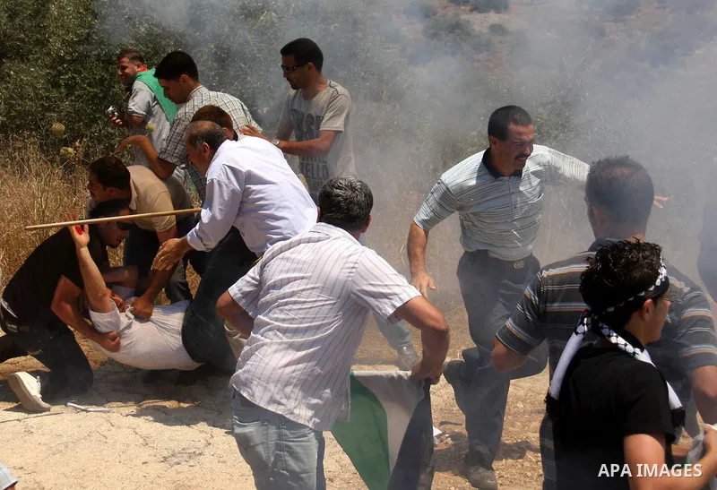 Palestinian villagers run for cover from tear gas fired by Israeli forces during clashes follo wing a protest against the closure of a road during the second Intifada by Jewish settlers from the nearby settlement of Kadu...