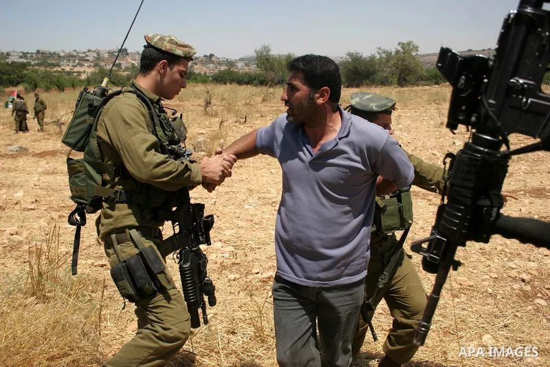 An Israeli soldier detains a protester during a demonstration by Palestinian, Israeli and foreign activists against the demolishing of farm land to be used in the construction of Jewish settlements near the existing Isra...