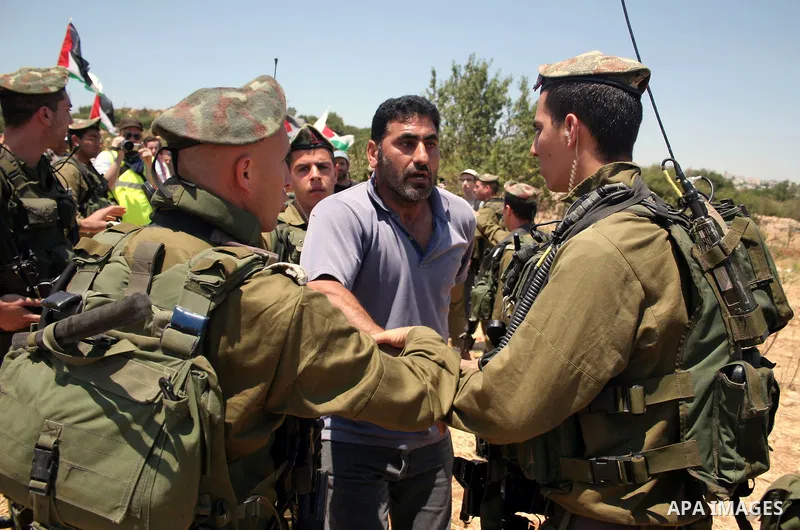 Israeli soldiers scuffle with a protester during a demonstration by Palestinian, Israeli and foreign activists against the demolishing of farm land to be used in the construction of Jewish settlements near the existing I...