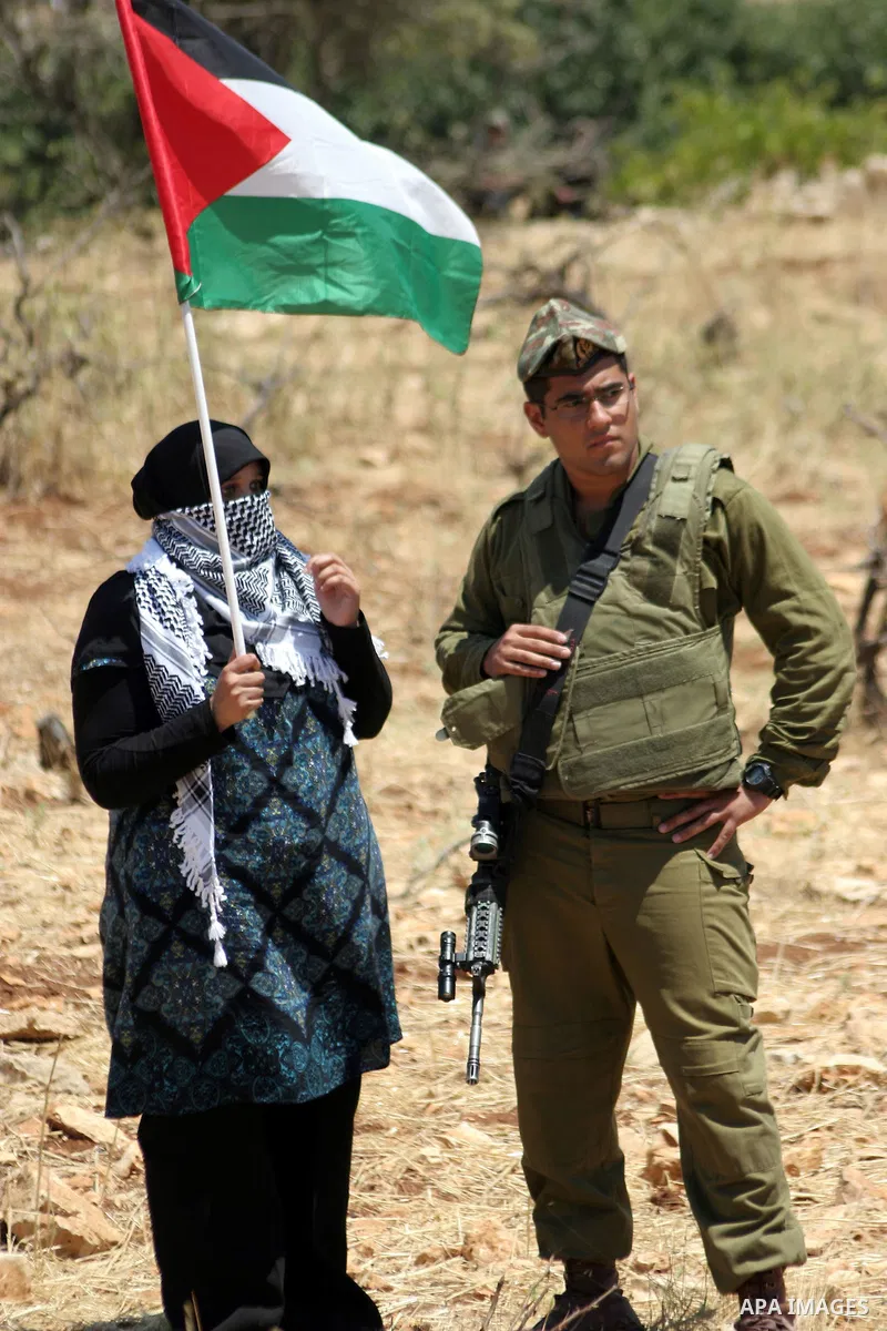 Israeli soldiers stand guard as Palestinian, Israeli and foreign activists take part in a demonstration against the demolishing of farm land to be used in the construction of Jewish settlements near the existing Israeli...