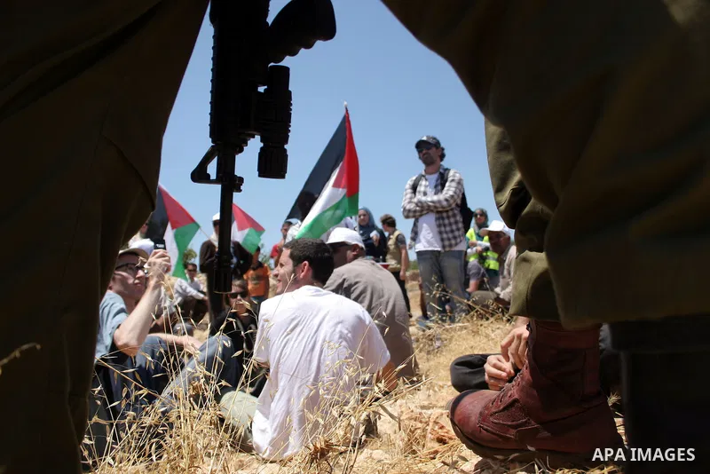 Israeli soldiers stand guard as Palestinian, Israeli and foreign activists take part in a demonstration against the demolishing of farm land to be used in the construction of Jewish settlements near the existing Israeli...