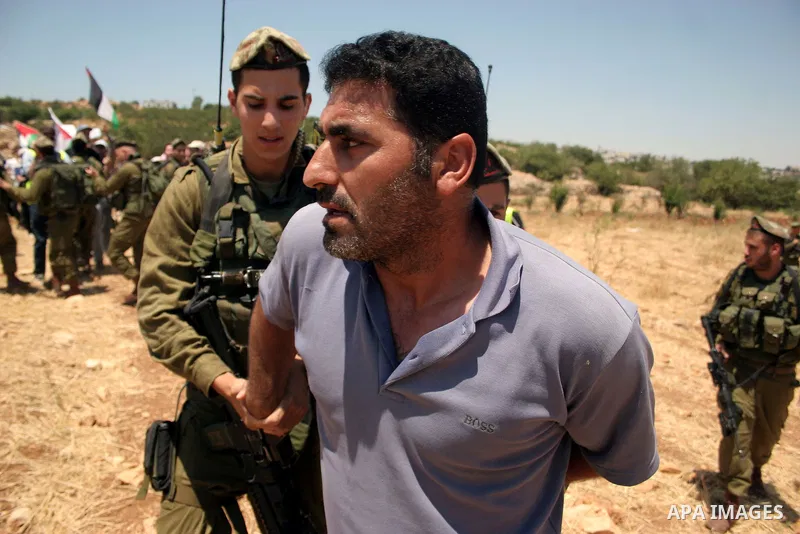 An Israeli soldier detains a protester during a demonstration by Palestinian, Israeli and foreign activists against the demolishing of farm land to be used in the construction of Jewish settlements near the existing Isra...