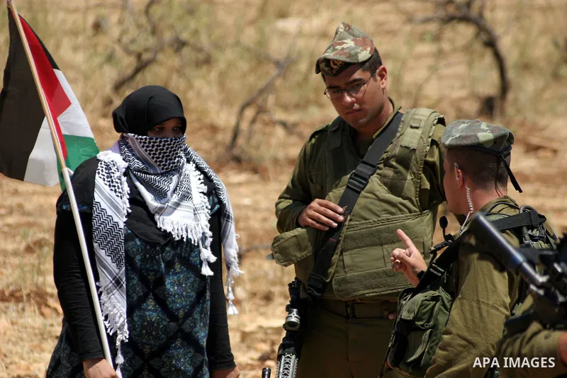 Israeli soldiers stand guard as Palestinian, Israeli and foreign activists take part in a demonstration against the demolishing of farm land to be used in the construction of Jewish settlements near the existing Israeli...