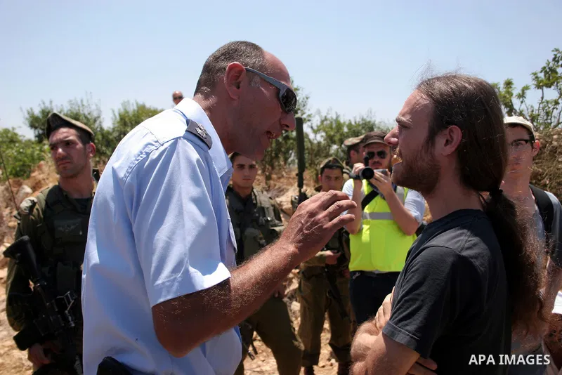 Israeli soldiers stand guard as Palestinian, Israeli and foreign activists take part in a demonstration against the demolishing of farm land to be used in the construction of Jewish settlements near the existing Israeli...