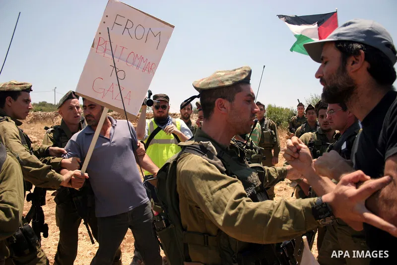 Israeli soldiers scuffle with a protester during a demonstration by Palestinian, Israeli and foreign activists against the demolishing of farm land to be used in the construction of Jewish settlements near the existing I...